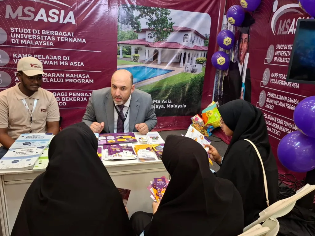 MS Asia adviser explaining university entry pathways to two students at an education fair